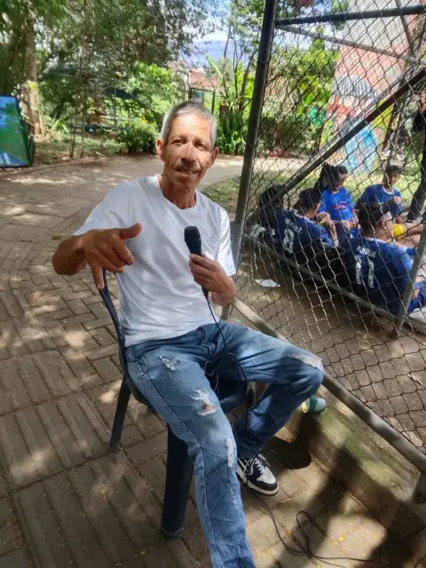 Jaime Ramirez sentado con el micrófono junto a un equipo de camiseta azul